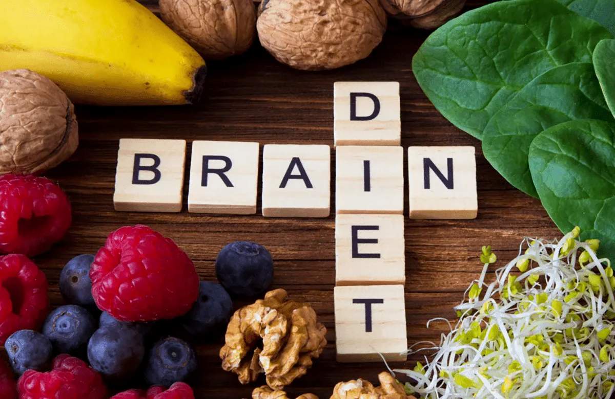 Wooden letter tiles spelling “BRAIN DIET” sit on a table surrounded by fruits, spinach leaves, walnuts, and sprouts—reflecting the focus on brain health at MorningStar Senior Living Hillsboro for vibrant retirement living.