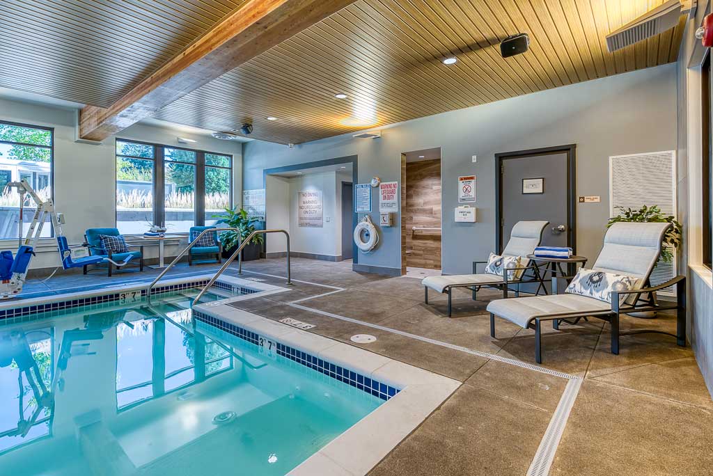 Enjoy the indoor pool at MorningStar Senior Living Hillsboro, featuring clear blue water, lounge chairs, and natural light—an inviting space for relaxation and wellness in retirement living.