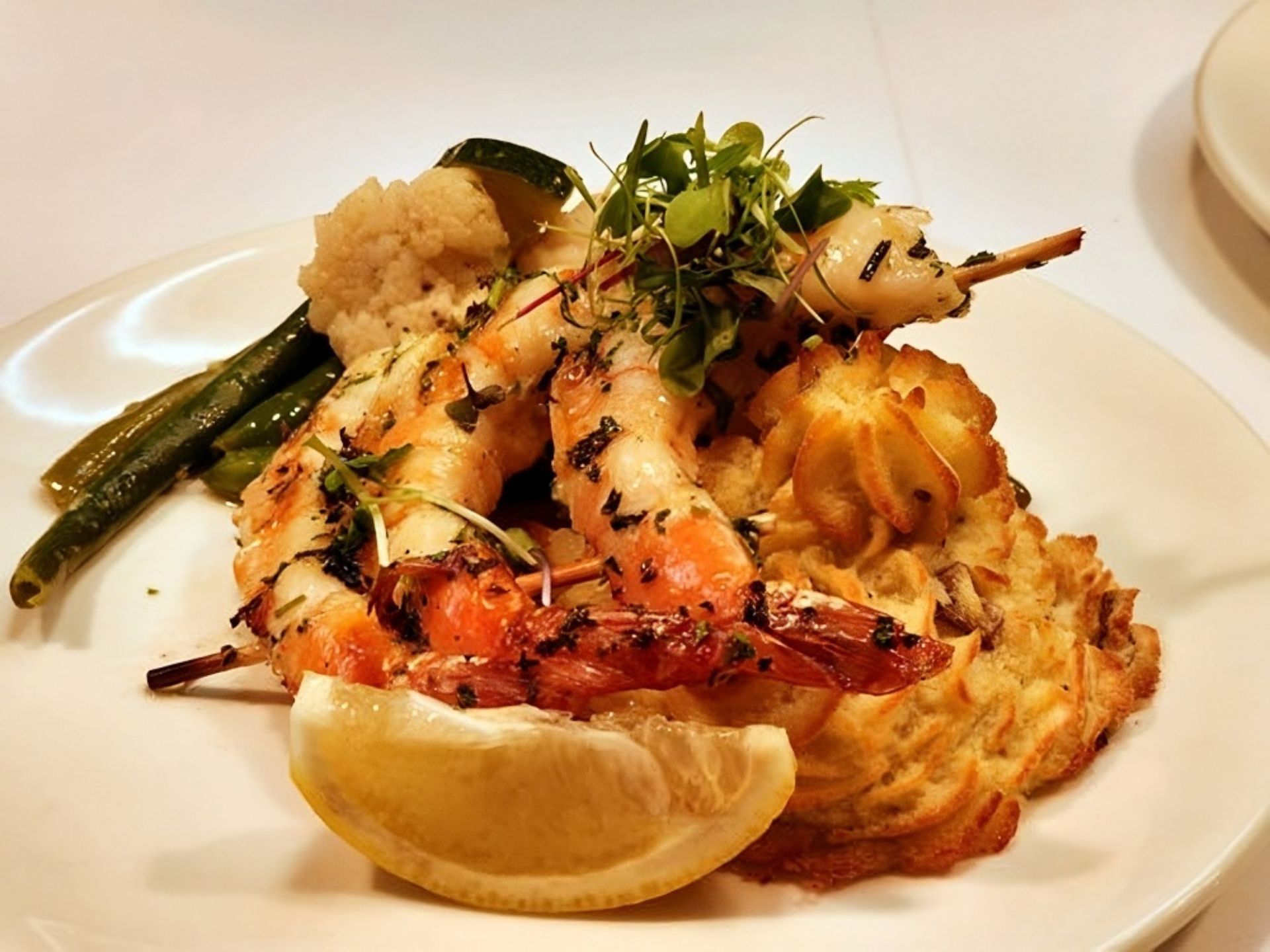 Grilled shrimp skewers served on a bed of piped mashed potatoes, garnished with microgreens and a lemon wedge, accompanied by cauliflower and green beans—a delightful dish at MorningStar Senior Living Hillsboro for an elevated retirement living experience.