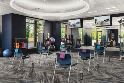 A modern fitness studio at MorningStar Senior Living Hillsboro features spaced chairs facing mirrors, each with a towel draped over the back. Exercise balls and dumbbells are organized on racks, making retirement living active and vibrant.